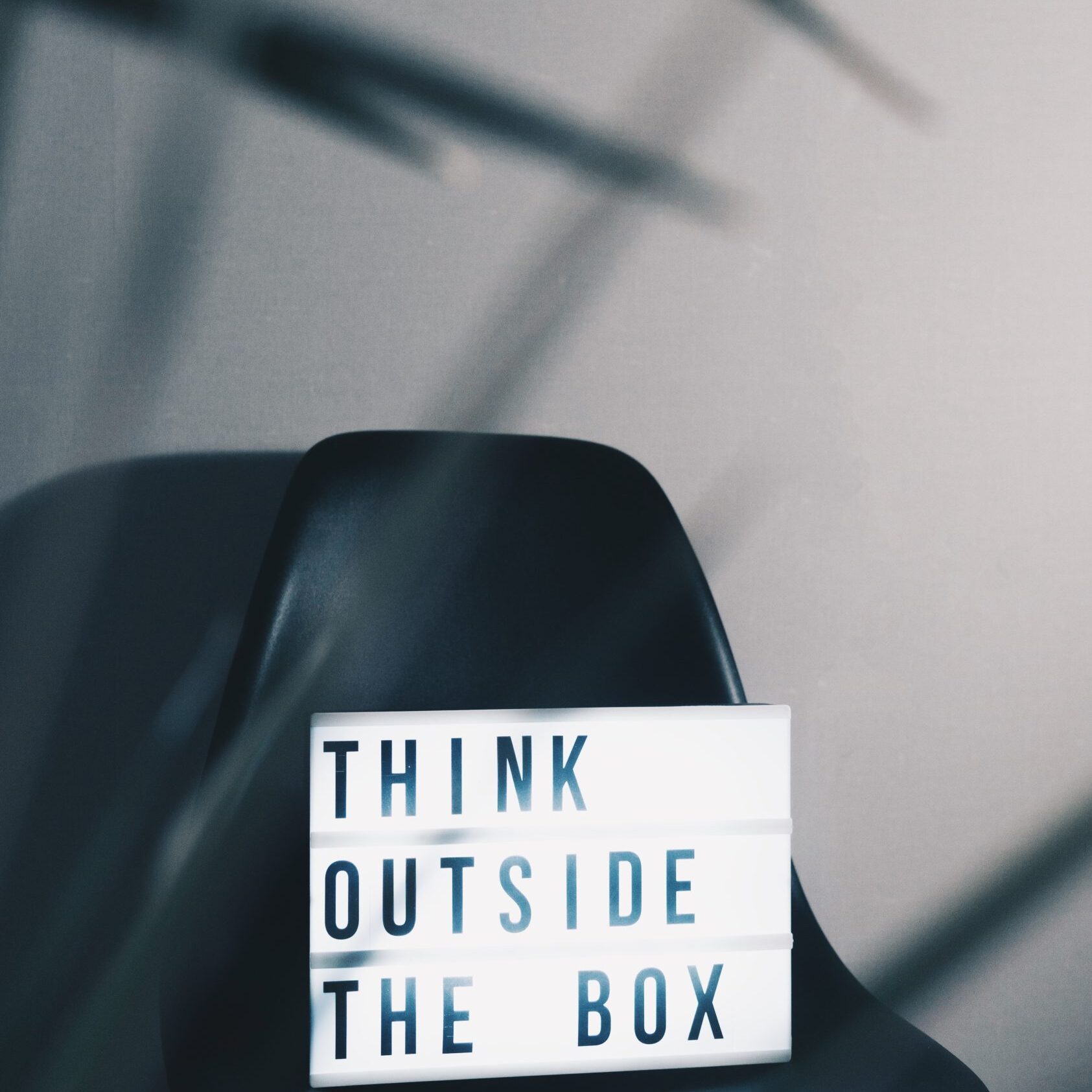 Chair in empty room with a sign that says think outside the box